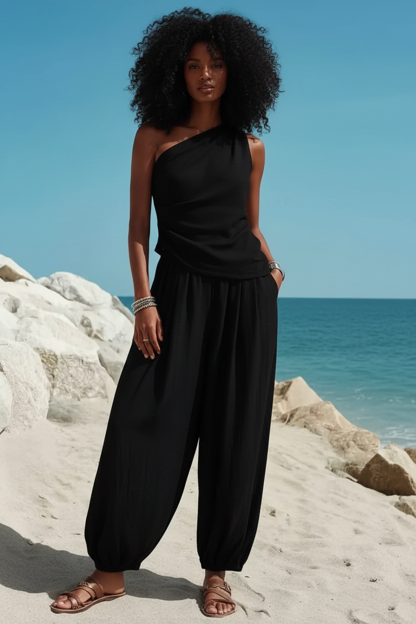 Black woman with curly hair in black outfit on beach